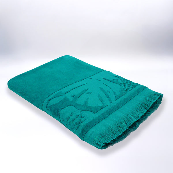 Serviette de plage ciselée bleue Kariba pliée, en velours jacquard doux et absorbant.