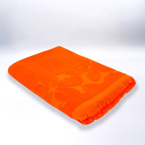 Serviette de plage ciselée orange Kerlaz pliée, en velours jacquard doux et absorbant.