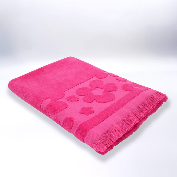 Serviette de plage ciselée rose Kervel pliée, en velours jacquard doux et absorbant.