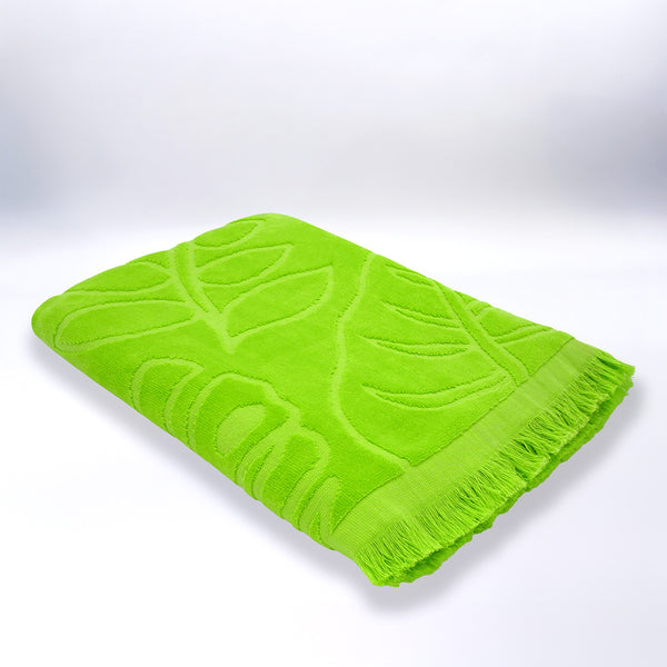 Serviette de plage ciselée verte Klang pliée, en velours jacquard doux et absorbant.