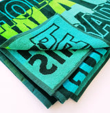 Serviette de plage Surfy textes thème surf allover coloris dégradés bleu-vert 95x175cm 440gm² 100% coton